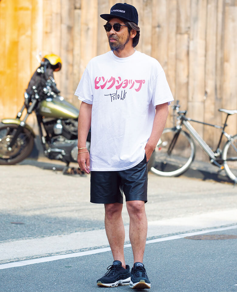 レザーショーツの男らしさを、意味深なメッセージが乗ったユーモアなTシャツで緩和。