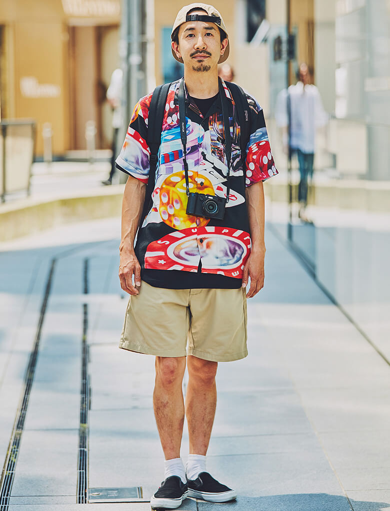 持ち物とたたずまいから醸されるアクティブ感。シャツは大胆不敵で只者じゃない感。