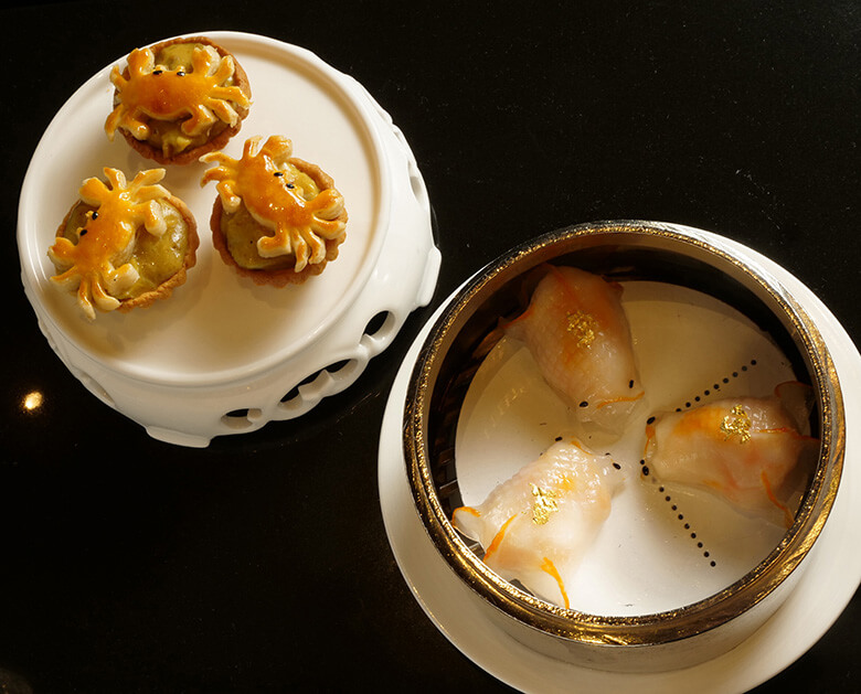 エビの蒸し餃子（Steamed Dumplings with Cristal Blue Shrimps in Goldfish Shape）」84パタカと、「カニ肉とカレーソースのタルト（Baked Tartelettes filled with Crabmeat in Curry Sauce）」66パタカ。