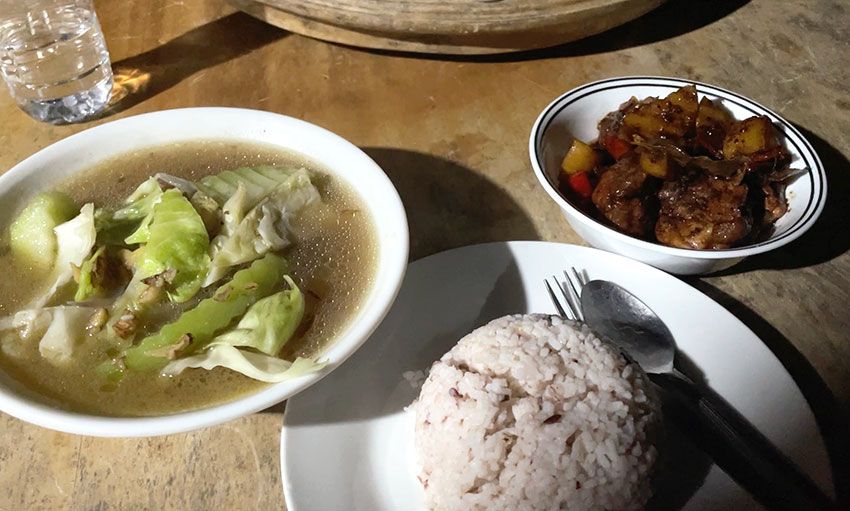 頻繁に停電し、暗闇で食べるご飯。おかずは右のアドボと左にウリとキャベツのコンソメスープ。