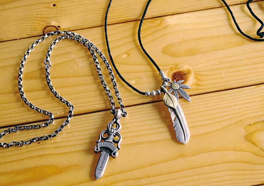 6年前に購⼊したというクロムハーツのネックレス（右）は、⼤きめのダガー（⼩剣）デザインがポイント。ゴローズのフェザーネックレス（右）は、おもにスーツを着⽤する際に合わせることが多いそう。
