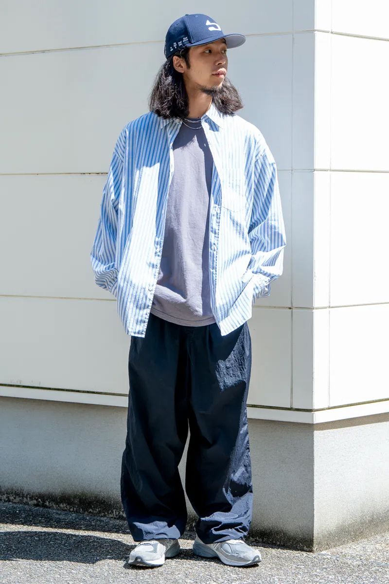 グラフペーパーのコーデ好例。上下ともにオーバーサイズなサイジングでまとめたコーディネイト。グレーのΤシャツの上に羽織ったライトブルーのストライプシャツが爽やかな印象だ。