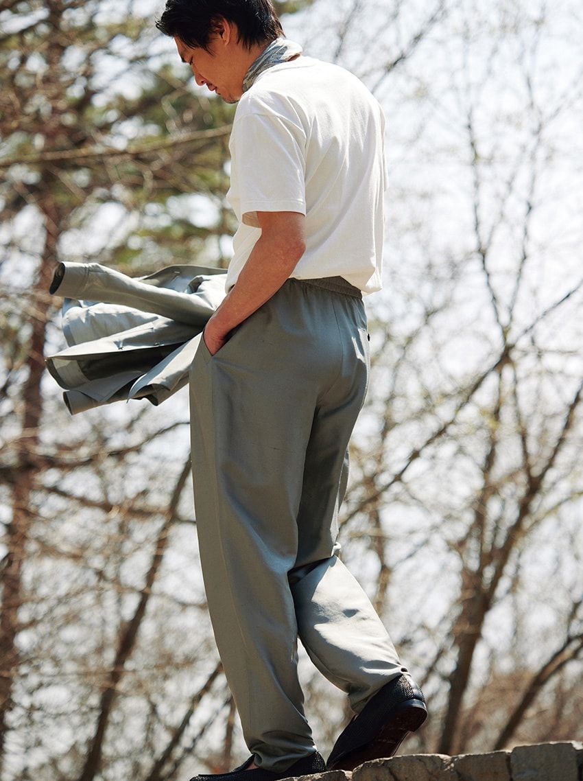 パンツ28万6000円、手に持ったジャケット44万円、靴15万4000円、スカーフ9万1300円／すべてジョルジオ アルマーニ（ジョルジオ アルマーニ ジャパン　03-6274-7070）