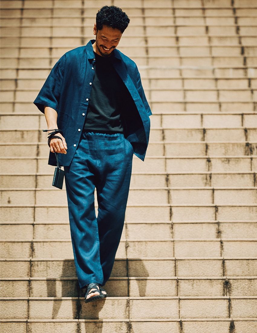 シャツ3万1900円、パンツ3万1900円／ともにRHC（RHC ロンハーマン　0120-008-752）、Tシャツ8万6900円／マッキントッシュ クラフテッド バイ バトナー（マッキントッシュ 六本木ヒルズ　03-5843-1580）、サンダル1万4960円／ザ・ノース・フェイス（ゴールドウインカスタマー　0120-307-560）、手に持った財布2万5300円／アティテュ（土屋鞄製造所　0120-907-647）
