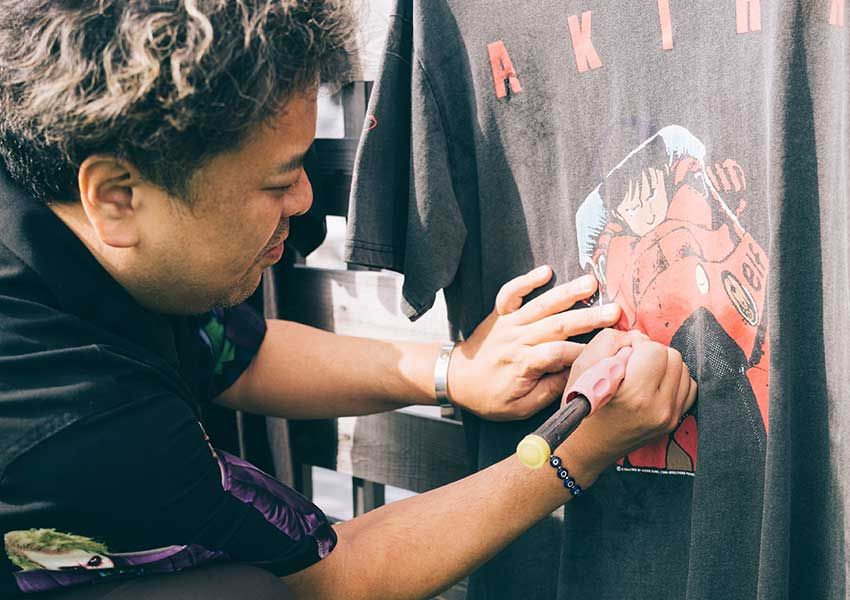 貴重なヴィンテージTシャツに対し、何のためらいもなく⼯具を使ってプリント部分を削り落とす久保⽥さん。⼯具以外には、やすりなども使うそう。