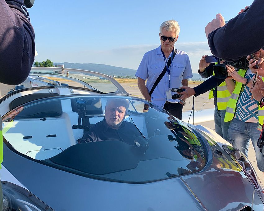 待ち構えた人々に出迎えられる飛行士兼ドライバーのクライン教授。