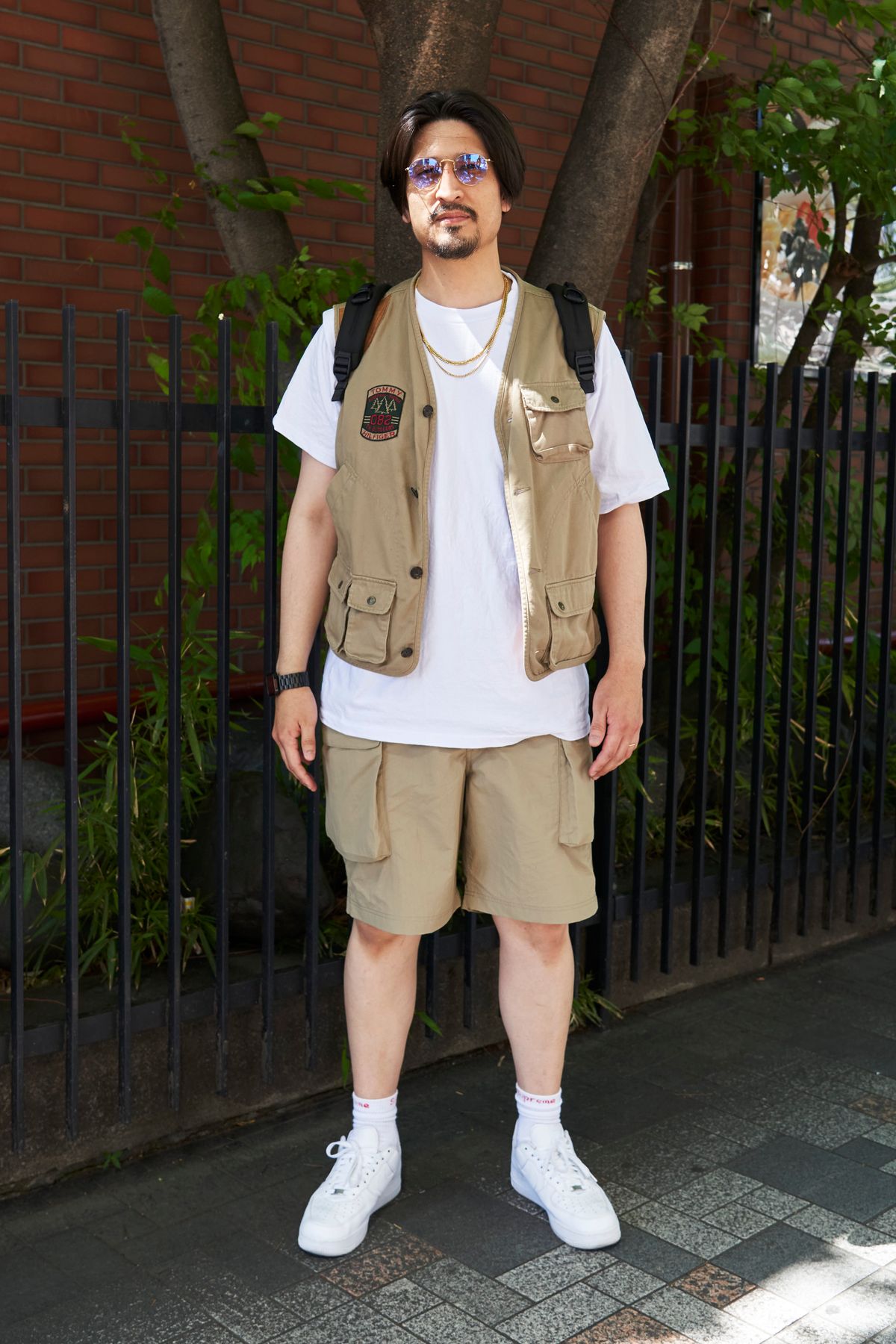 ベスト=トミーヒルフィガー Tシャツ=プロクラブ パンツ=ユニクロ シューズ=ナイキ×シュプリーム 眼鏡=レイバン バッグ=トゥミ 腕時計=アップル リング=スタージュエリー