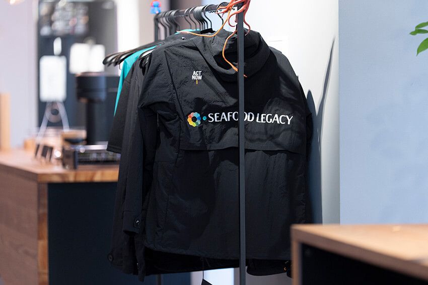 シーフードレガシーのオフィスに置かれていたスタッフユニフォーム。オーシャンズでも以前取り上げたアップサイクルブランド「エコアルフ（ECOALF）」のものに刺繍が施されたものだった。