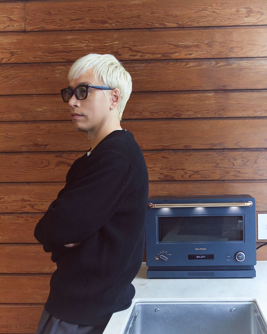 「バルミューダ ザ・レンジ」を背に。シンプルな操作方法はそのままに、レンジ・オーブンの加熱性能が向上したニューモデルだ。ダイヤルを回すとギターの優しい音色が鳴り、キッチン周りに楽しげなムードをプラスしてくれる。5万9400円〜／バルミューダ