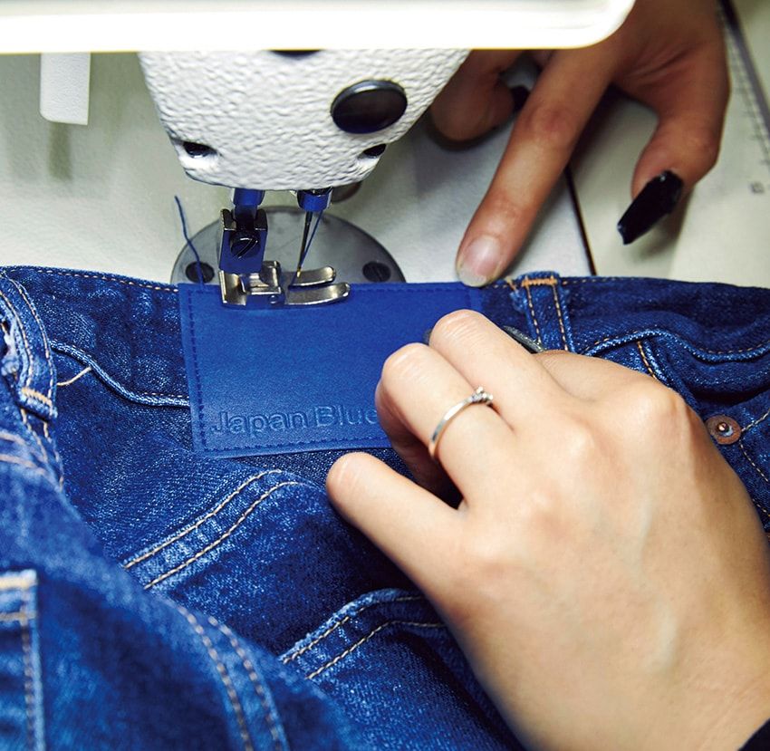 レザーパッチの縫い付け。加工に響く素材は、劣化を防ぐため、縫製工場で形を整えてから加工場へ出し、再び縫製工場に戻る。児島ならではの距離感が、このフローを可能にしている。