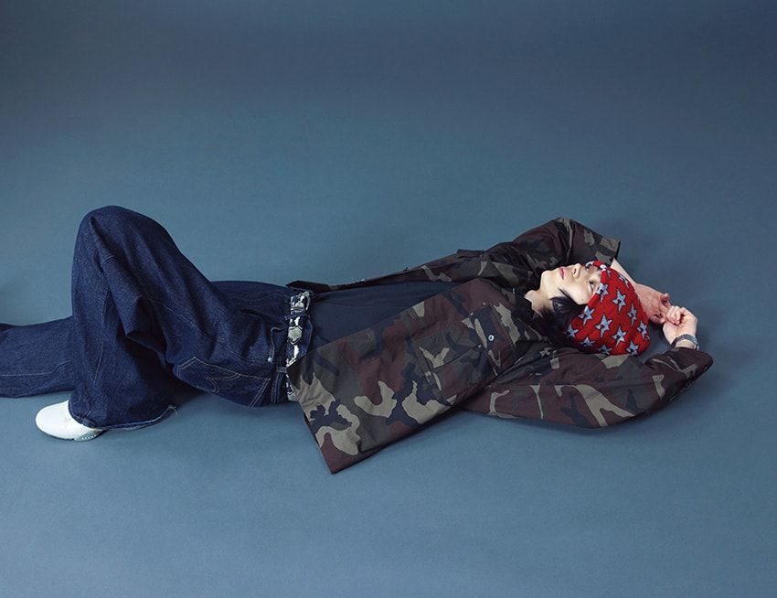 プライベートで愛用しているエドウインのワイドストレートのデニムパンツは、トレンド感のあるルーズフィットが気分。ゆとりのあるシルエットが肩の力の抜けた佇まいを演出する。トップには赤のニットキャップと迷彩柄シャツをチョイスし、上下でコントラストを楽しむ。ラフさの中にも個性が光る、菅田さんらしいデニムスタイルだ。デニム、スニーカー、腕時計／すべて本人私物、シャツ4万9500円／レスレストン　06-6448-8330、Tシャツ1万5000円／カールソン ワッチ（ゼロゼロ　03-6434-5470）、帽子9900円／カーペット カンパニー（ブラック ボックス　03-5843-0669）