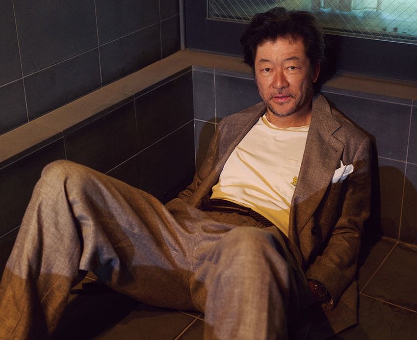 貫禄と色気が宿るダブルブレストだが、リネン素材ゆえ軽やかなムードに。ドレープの効いたパンツが動きに余白を生み、全体をエフォートレスにまとめている。私物で合わせたユニクロのポケTも違和感なく馴染んでいる。ジャケット53万9000円、パンツ26万4000円、ベルト7万1500円／すべてジョルジオ アルマーニ（ジョルジオ アルマーニ ジャパン　03-6274-7070）