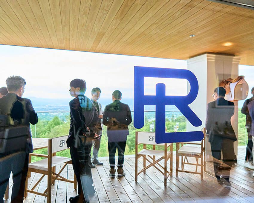 眺望のひらけたテラスで交わされる名刺と会話。RLのロゴの向こうに、軽井沢の山並みが静かに広がっていた。
