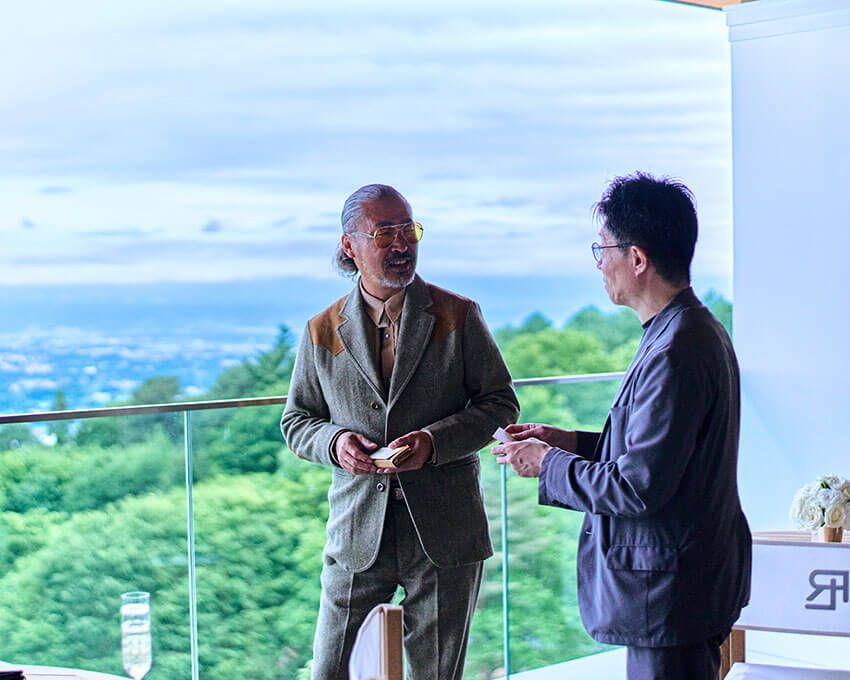 山々を背に、立ち話が続く。半分プライベートで半分仕事のような時間が、思いがけない出会いを連れてくる。