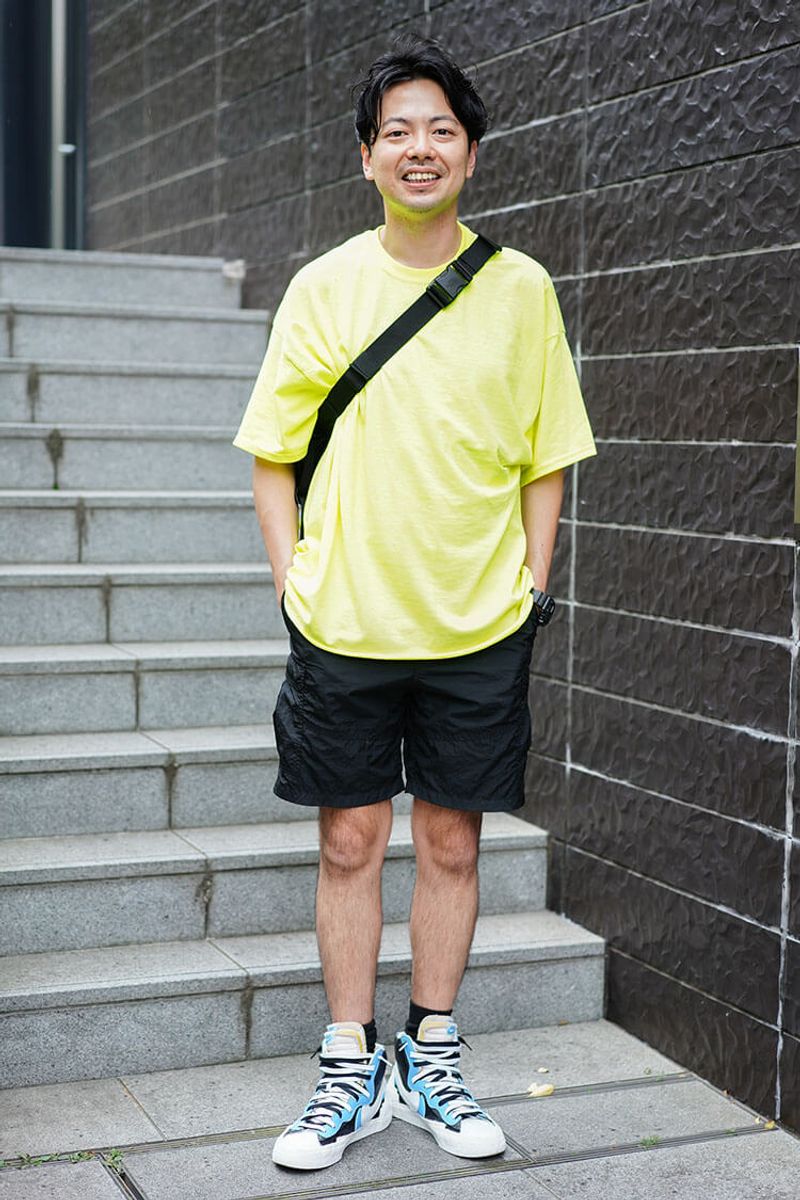 カラーTシャツとボリュームスニーカーを、黒のショーツで引き締める 成家保仁