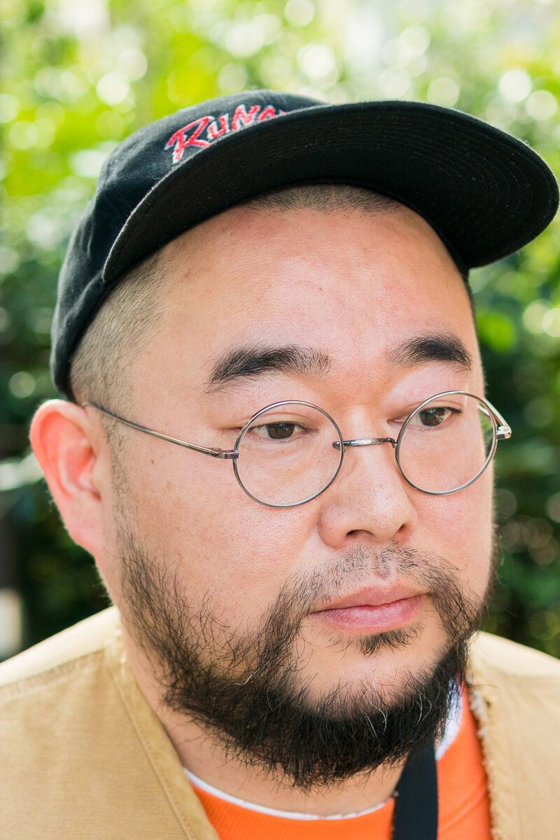 ブラックパンツとベージュトップスの王道コーデを、オレンジで一気にポップに！ 荒井将平 2枚目の写真