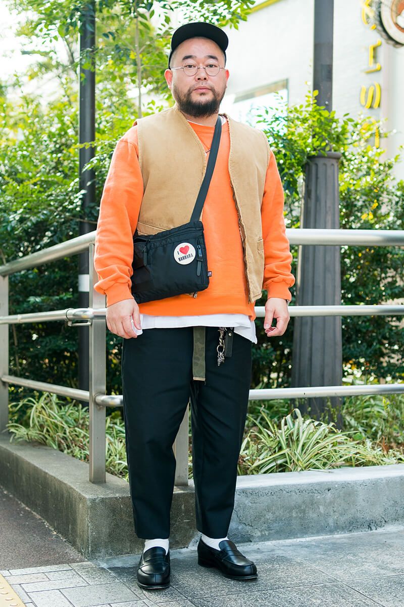 ブラックパンツとベージュトップスの王道コーデを、オレンジで一気にポップに！ 荒井将平