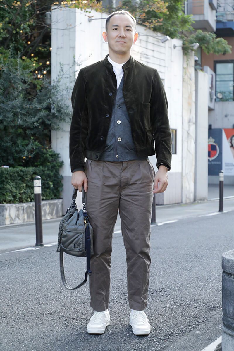 巾着バッグはやっぱりいいアクセント。ナイロン製のグレーカラーで可愛げ◎ 渡部慎也