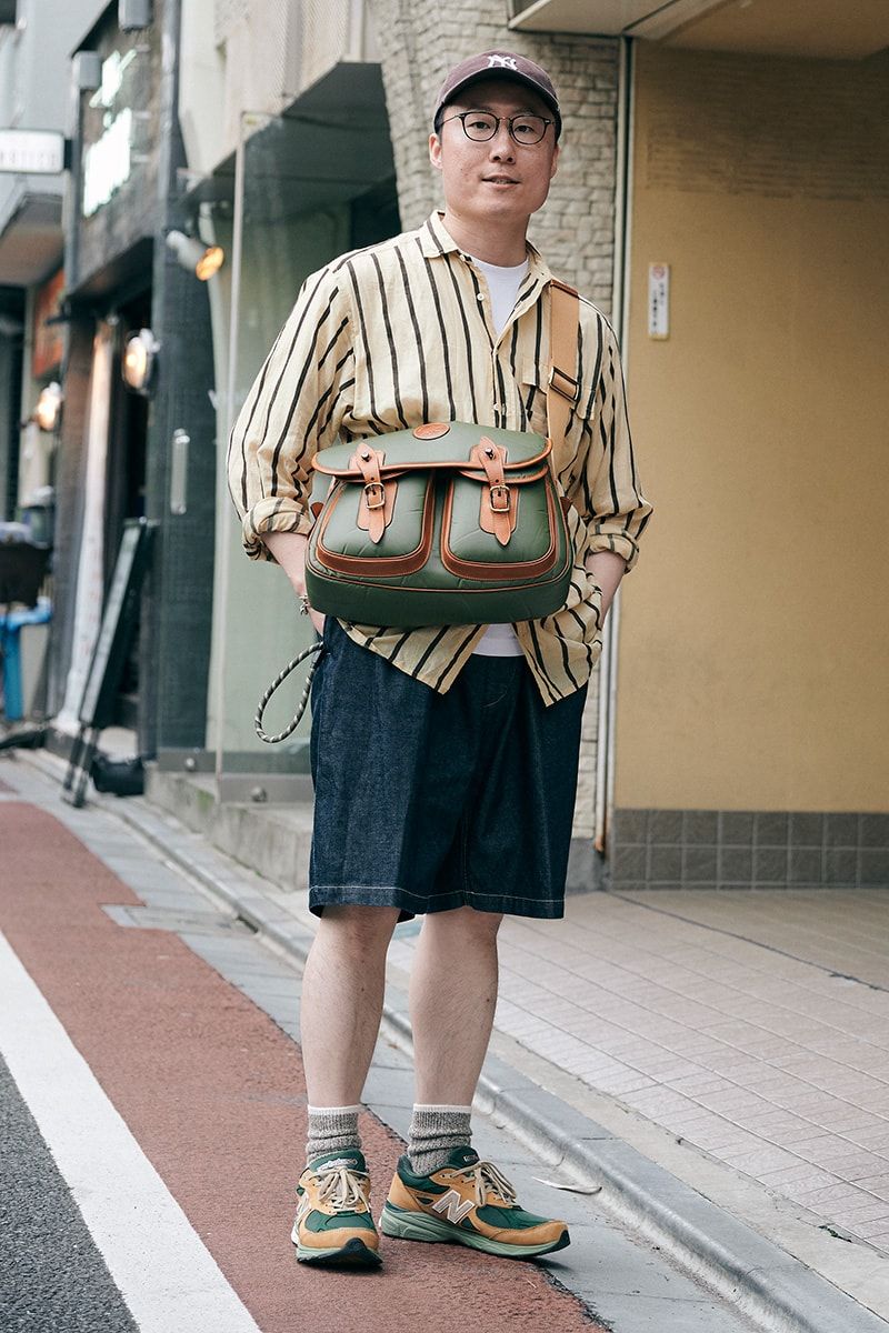 ブラウン系ストライプシャツにデニムショーツ、スニーカーとバッグは色合わせで コンドウ