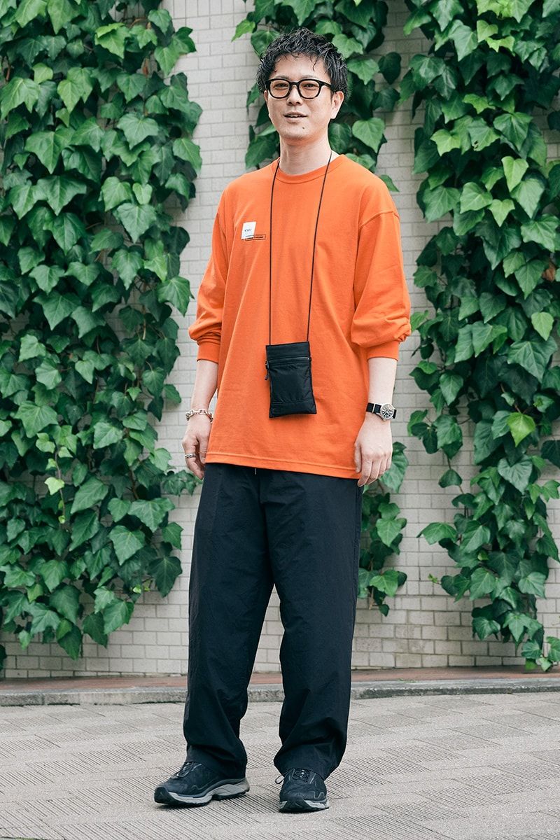 フレッシュなオレンジトップスを黒ポーチで引き締めたロンTコーデ 島田智明